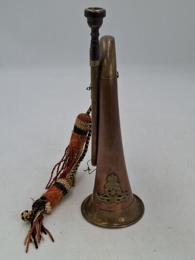 Vintage copper and brass military bugle horn with artillery badge.