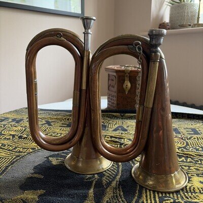 A pair of vintage copper and brass bugles, different styles and sizes